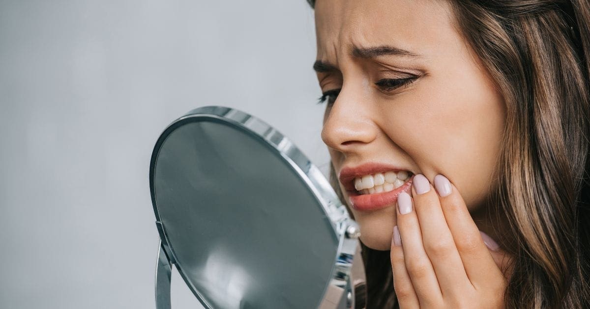 donna che ha male e si chiede cosa fare per evitare la formazione di carie