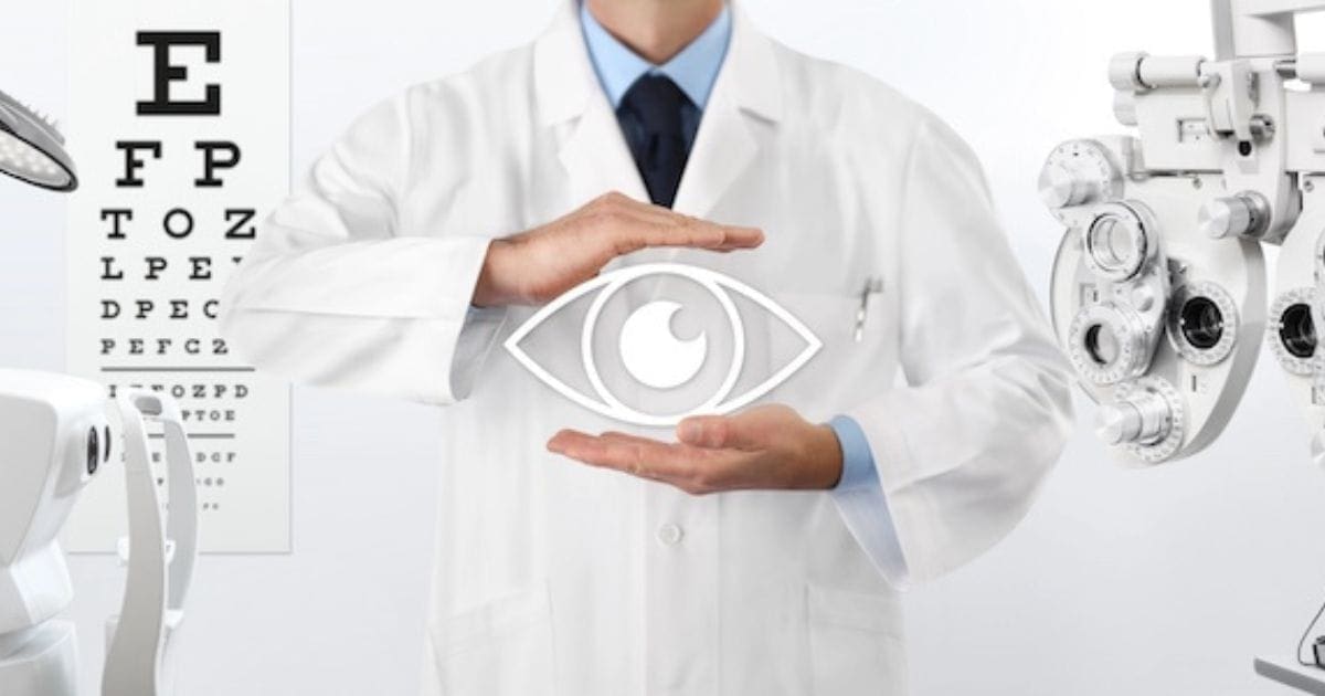 oculista in camice tiene un occhio disegnato in mano, sullo sfondo le apparecchiature per l'oculista