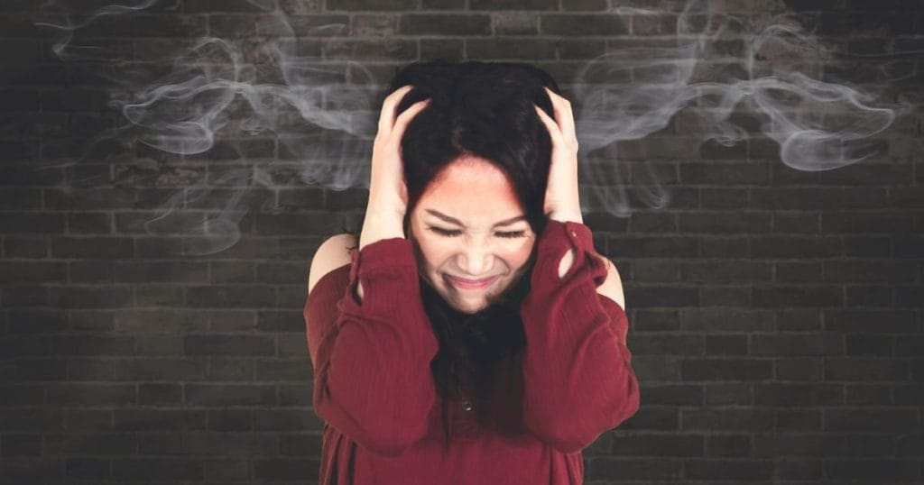 donna si tiene le mani tra i capelli con fumo disegnato sopra la testa