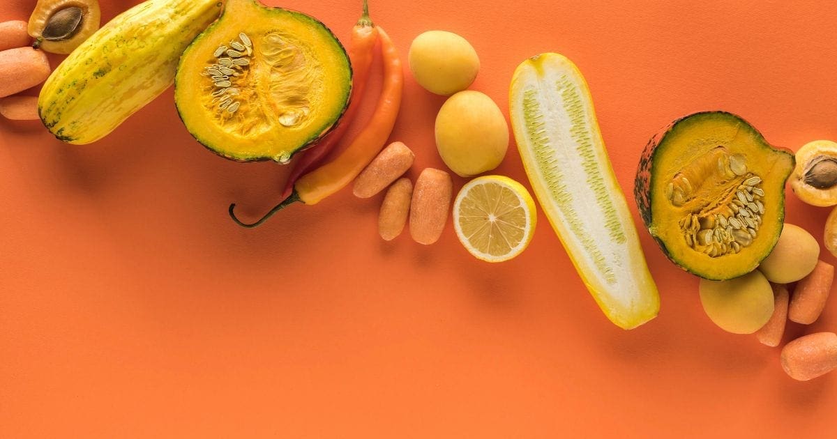 frutta e verdura di colore giallo e arancione su sfondo arancione come zucca, peperone, carote