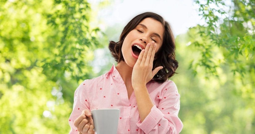 donna sbadiglia con una tazza di caffè in mano