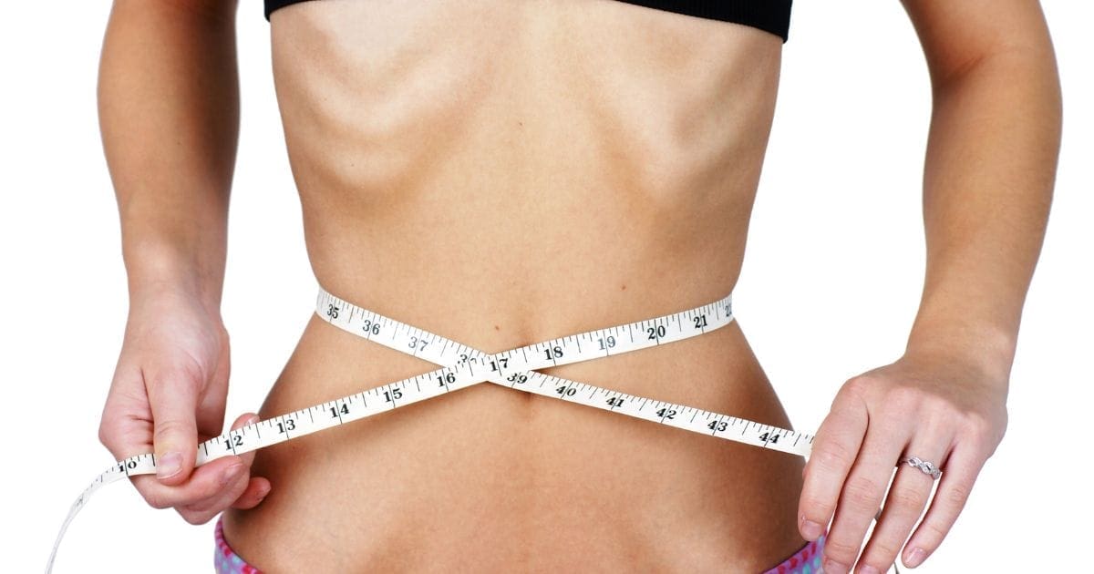 donna molto magra con metro per misurare la circonferenza della vita